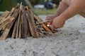Close up view of male hands holding matches near the firewoods. Man making fire outdoors.