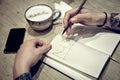 Close-up view of male hands with note book and coffee draw diagramms Royalty Free Stock Photo