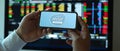 Male office worker holding mock up horizontal smartphone at working desk