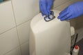 Close up view of man in blue gloves putting refreshing stick into toilet stool system