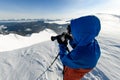 close-up view of man with camera taking pictures of beautiful winter mountain landscape
