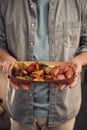 Close up view. Man in casual clothes is holding food that are in the paper eco box. Potatoes, sausages, mushrooms, zucchini Royalty Free Stock Photo