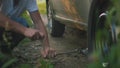 Close up view of man changes broken wheel of a car in the woods Royalty Free Stock Photo