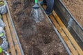 Close up view of man in greenhouse watering deepening in garden bed before planting plant.