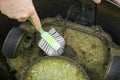 Close up view of man hand brushing off layer of wet grass stuck under automated lawnmower.