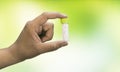 Close-up view of a man hand holding a bottle of homeopathic pills on a mix green yellow background