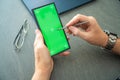 Close up view of man hand holding smart phone with green chroma key screen and stylus pen at his creative workspace Royalty Free Stock Photo