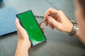 Close up view of man hand holding smart phone with green chroma key screen and stylus pen at his creative workspace Royalty Free Stock Photo