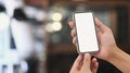 Close up view of man hands holding mock up smart phone with cafe blurred background. Royalty Free Stock Photo