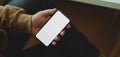 Close-up view of man holding blank screen smartphone while sitting his comfortable office Royalty Free Stock Photo