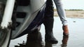 Close-up view of the man leg in the gumboots and woman one in highheels getting off the motorbike on the puddles.