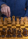 Close-up view of a man playing chess on an ancient wooden chess board Royalty Free Stock Photo