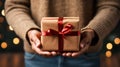 Close-up view of a man\'s hands holding a Christmas present, with festive lights glowing in the background Royalty Free Stock Photo