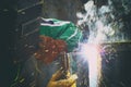 Close up view on man with weld mask during weld work with sparks all around