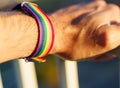 close-up view of a man& x27;s hand with an LGBT rainbow wristband.