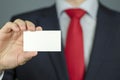 Close-up view of a manager`s hand in a suit and with a red tie holding an empty business card