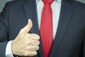 A close-up view of a manager`s hand in a suit and tie with thumb up