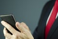 Close-up view of manager in suit with red tie holding smartphone with leather