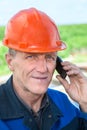 Close-up view of mature manual worker in hardhat calling on the phone