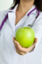 Close up view of medical doctor hand offering green apple Royalty Free Stock Photo