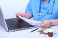 Close-up view of medical doctor working table. Laptop, stethoscope, assorted pils and patient information form Royalty Free Stock Photo