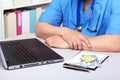 Close-up view of medical doctor working table. Laptop, stethoscope, assorted pils and patient information form Royalty Free Stock Photo