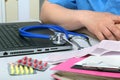 Close-up view of medical doctor working table. Laptop, stethoscope, assorted pils and patient information form Royalty Free Stock Photo