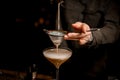 close-up view on sieve through which male bartender pours frothy espresso martini cocktail into glass Royalty Free Stock Photo