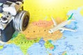 Miniature Airplane and Vintage Mirrorless Camera on World Map Background