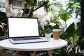 Mock up laptop computer with white screen on round table at outdoor cafe. Royalty Free Stock Photo