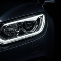 A close-up view of a modern car headlight in a dimly lit setting. The headlight features Royalty Free Stock Photo