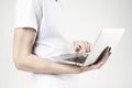 Close-up view of modern laptop in man`s hands, guy wearing white t-shirt, working on portable computer. White background in studio Royalty Free Stock Photo