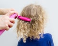 Close up view of mother hands spray curly hair balm on to girl child hair to help combing messy curly hair concept.