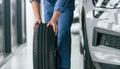 Close up view. Moving the tire. Man in blue uniform is working in the car service Royalty Free Stock Photo