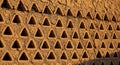 Mud brick wall with triangular perforations casting shadows in earthy architecture Royalty Free Stock Photo