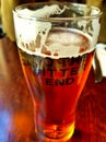 Close up view of mug of cold beer and TO THE BITTER END lettering on a wooden table in ireland Royalty Free Stock Photo