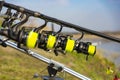 Close up view of multiple carp fishing reel coil on rods on rod pod near lake river. Fishing during sunset Royalty Free Stock Photo