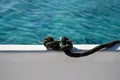 Close-up view nautical rope secured on cleat against blue sea. Rope is fixed to side of yacht.  Copy space. Royalty Free Stock Photo