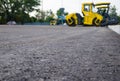 Close up view on the new asphalt road on which steamroller is working. Construction site.