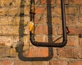 Close up view of an old rusty gas pipe with a faucet. Red brick on a peeling wall. Royalty Free Stock Photo