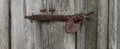 Close up view of the old rusty padlock on a aged gray wooden door Royalty Free Stock Photo