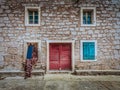 Close up view of old stone house, red wooden door and blue windows Royalty Free Stock Photo