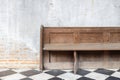 Close up view of old wooden bench on checkered pattern marble tiles floor with brick and cement wall background in church Royalty Free Stock Photo