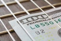 Close up view on a one hundred dollars, laid between the strings of acoustic guitar. Concept Royalty Free Stock Photo