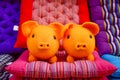 Close-up view of a pair of funny little pigs knitted with orange wool among colourful chairs
