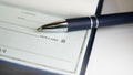 Close-Up view of a pen resting on a blank check on a desk Royalty Free Stock Photo