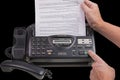 Close up view of person`s hands sending fax on Panasonic fax phone isolated on black background.