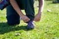 Person tying shoelaces outdoors in nature.