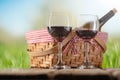 Close-up view of picnic basket with wine glasses of red wine stands on wooden rustic table on green garden background. Concept of Royalty Free Stock Photo