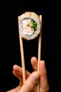 Close-up view of piece of roll california with snow crab meat, cream cheese, cucumber garnished sesame seeds in bamboo